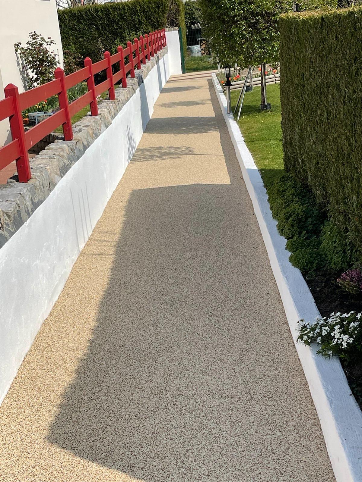 Allée piétonne en résine EPDM le long d'une clôture